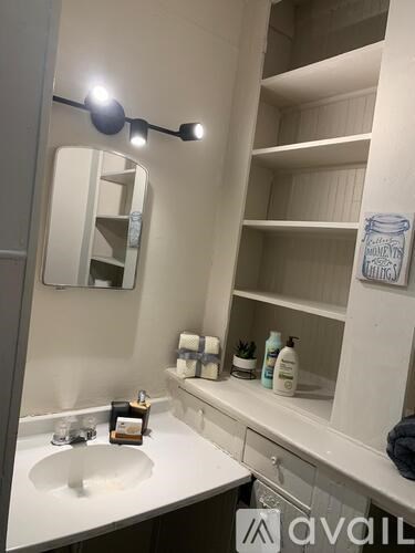 A bathroom with a white sink and a mirror with lights above it.