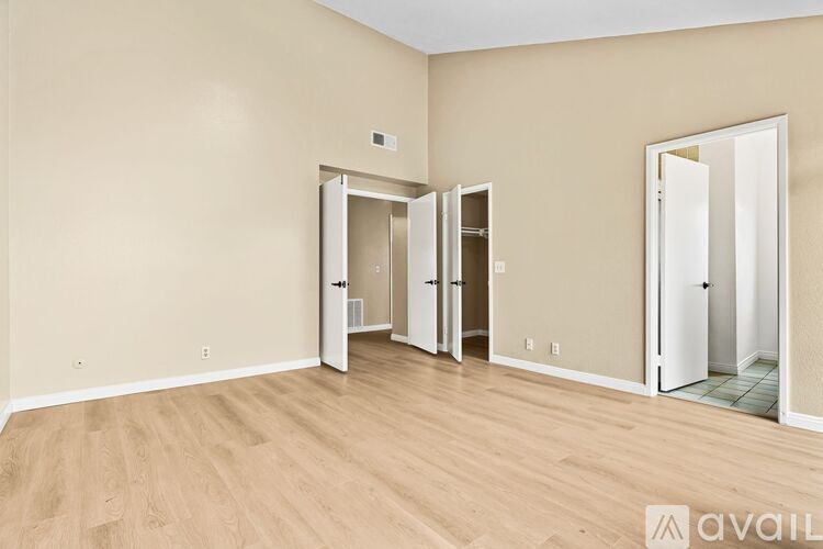 A room with wooden flooring and three open doors.