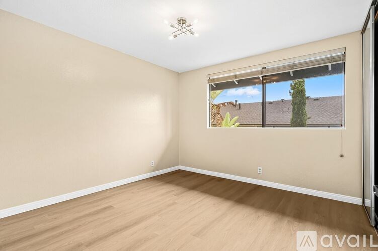 A room with a window showing a view of a tree and a house.
