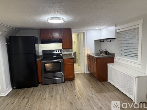 A kitchen with wooden floors and a black refrigerator.