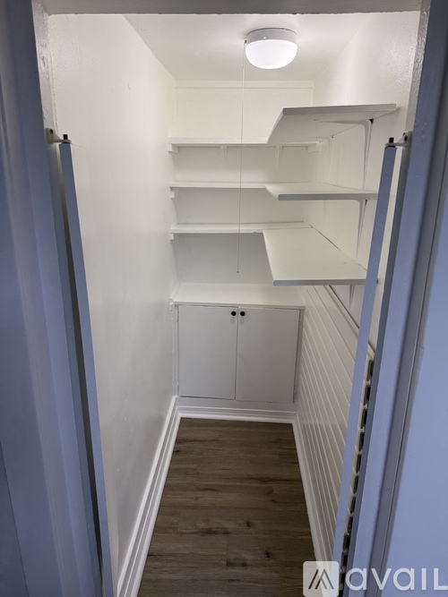 A narrow hallway with white shelves and a cabinet.