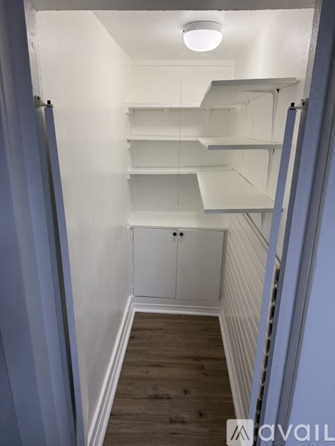 A narrow hallway with white shelves and a cabinet.