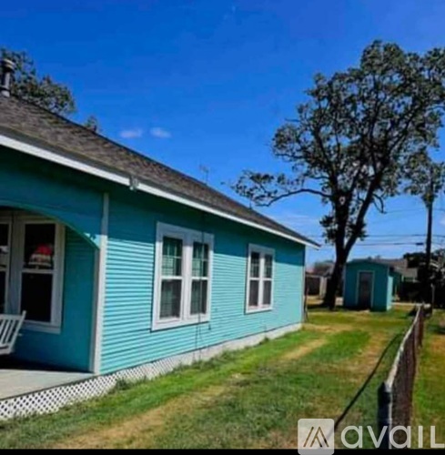A blue house with a white chair on the porch.
