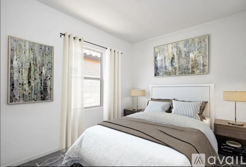 A bedroom with a large bed and two paintings on the wall.