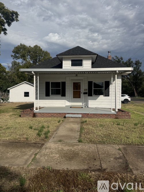 A white house with a black roof and a porch.