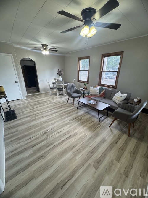 A living room with a couch, chairs, and a ceiling fan.