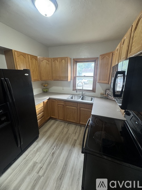 A kitchen with black appliances and wooden cabinets.