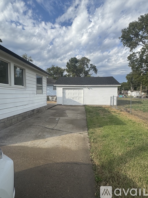 A white house with a garage is situated in a grassy area.