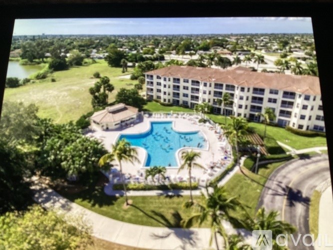 A large apartment complex with a pool in the middle of a grassy area.