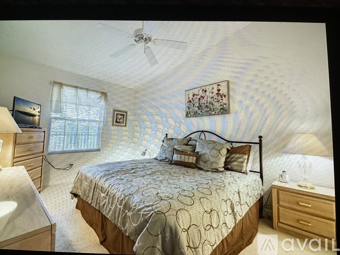 A bedroom with a bed, dresser, and ceiling fan.