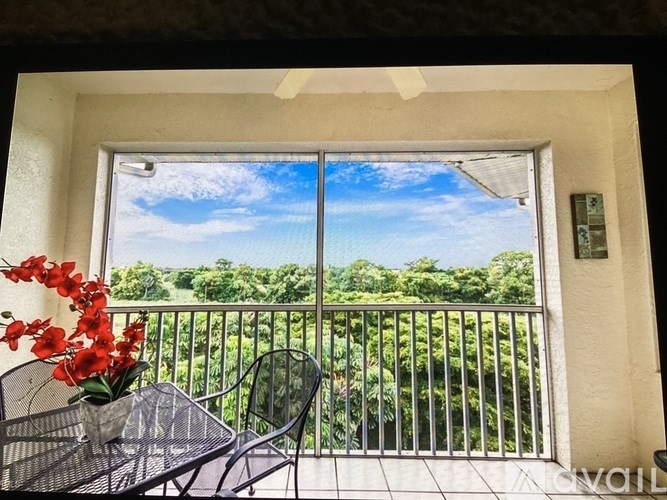 A balcony with a table and chairs overlooking a green landscape.