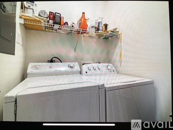 A washing machine is in front of a shelf with various items on it.