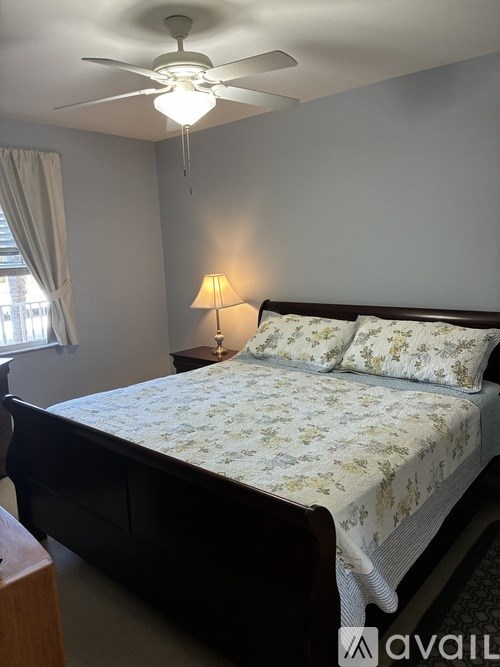 A bedroom with a bed, a ceiling fan, and a lamp.