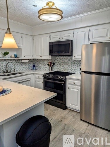 A kitchen with white cabinets and a stainless steel refrigerator.