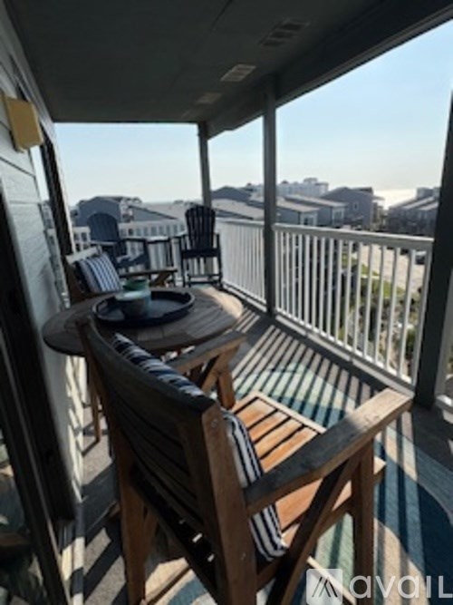 A wooden chair and table are on a balcony.