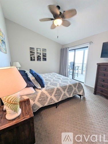 A bedroom with a bed, dresser, and ceiling fan.