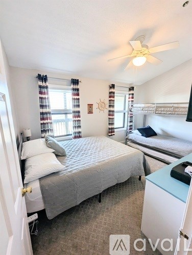 A bedroom with a bed, a desk, and a ceiling fan.