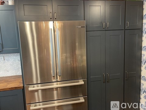 A stainless steel refrigerator with two doors and two drawers in a kitchen.