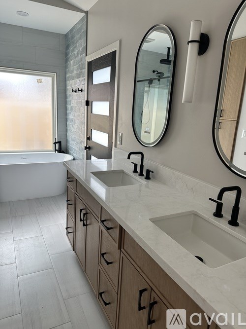 A bathroom with a tub, sink, and mirror.