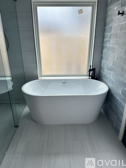A white bathtub is in a bathroom with a glass shower door.