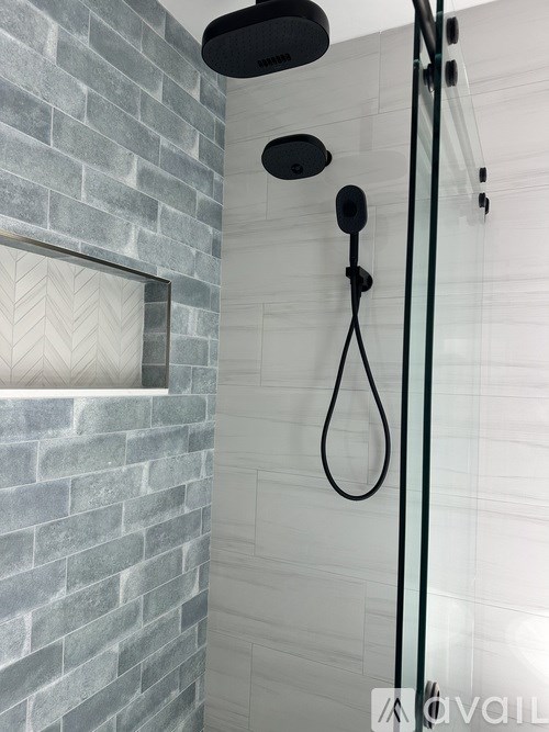 A shower with a glass door and a black shower head.