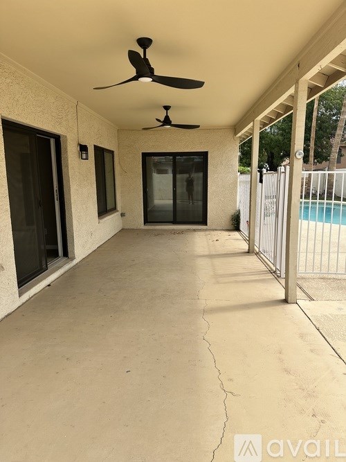 A patio with a ceiling fan and a pool in the background.