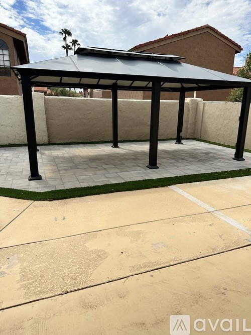 A patio with a black roof and a concrete floor.