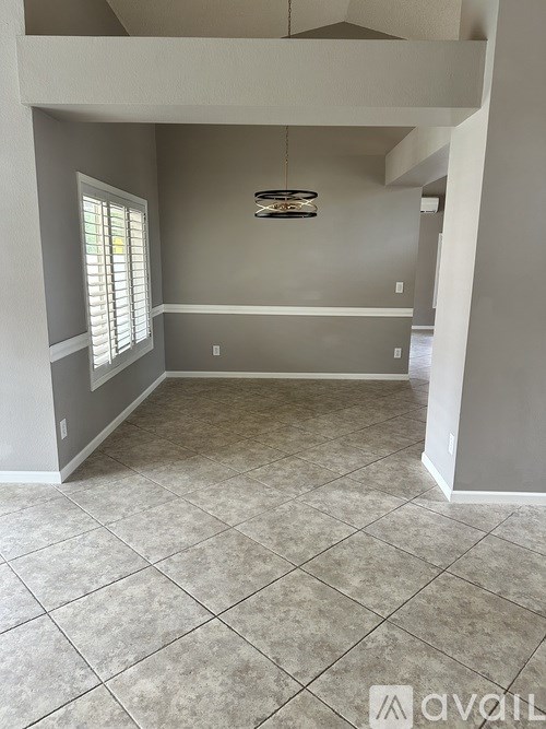 A room with tiled flooring and a window with blinds.