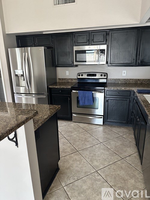 A kitchen with black cabinets and a granite countertop.