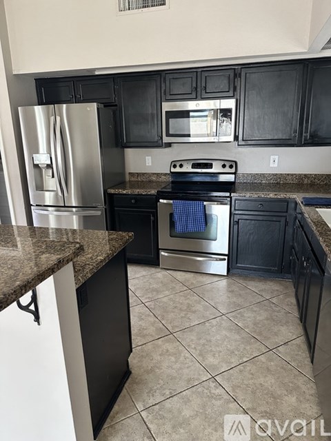 A kitchen with black cabinets and a granite countertop.