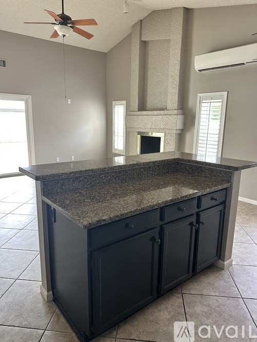 A kitchen island with a granite countertop and black cabinets.