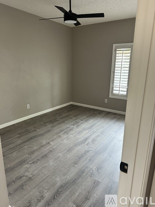 A room with a ceiling fan and a window with blinds.