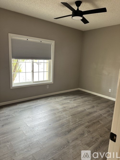 A room with a ceiling fan and a window with blinds.