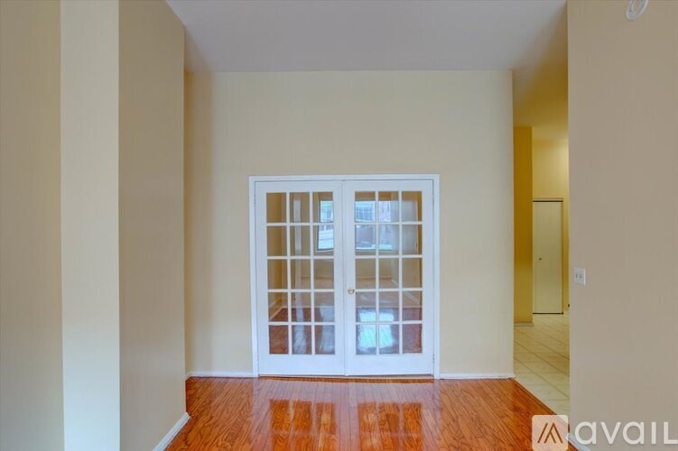 A room with a white door and wooden floor.