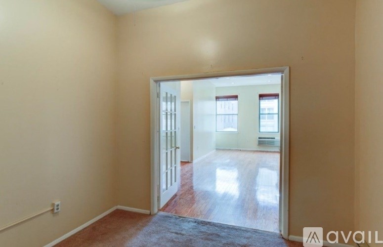 A room with a carpet and a doorway leading to another room.