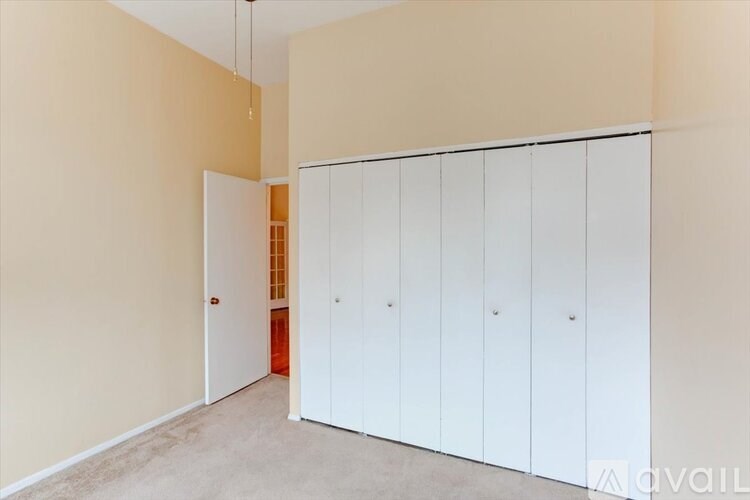A room with a white door and a row of white cupboards.