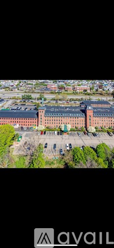 A large building with a green roof and a parking lot in front.