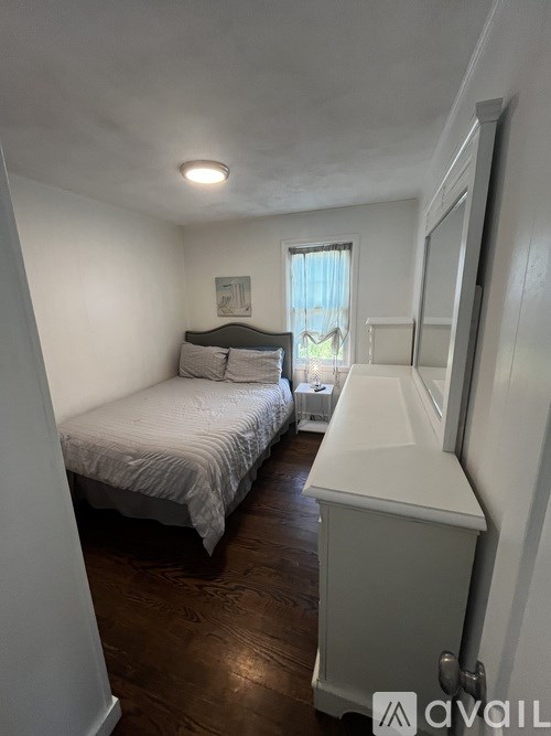 A bedroom with a bed, dresser, and window.