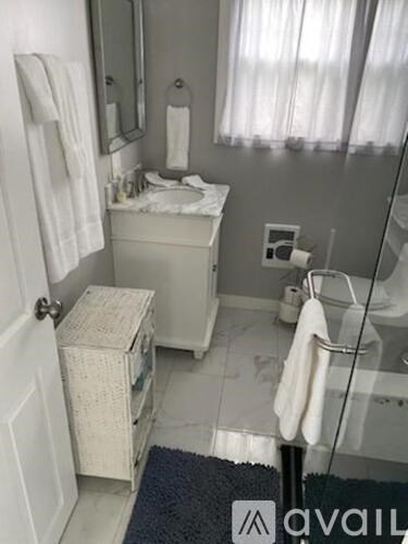 A bedroom with a bed, a window with curtains, and a painting on the wall.