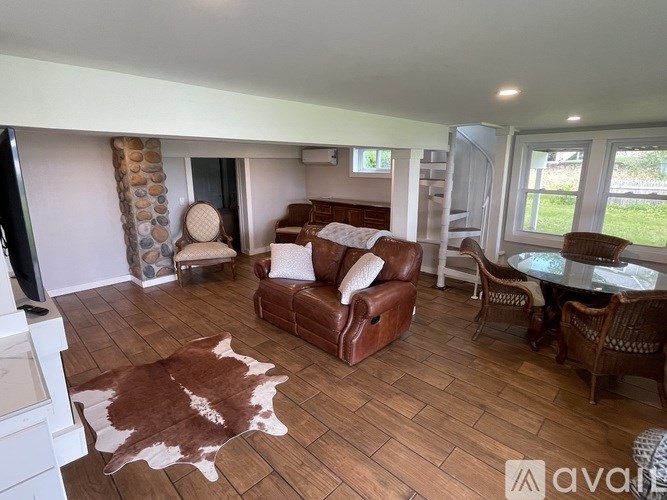 A living room with a brown cowhide rug and a brown leather couch.