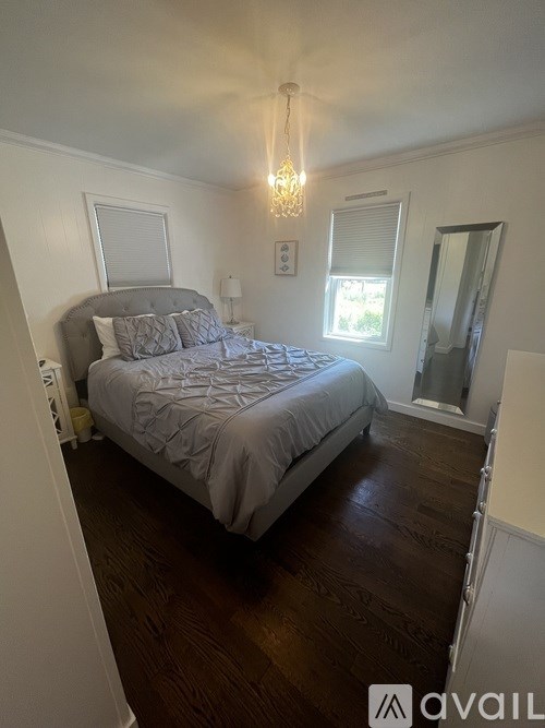 A bedroom with a bed, a chandelier, and a mirror.