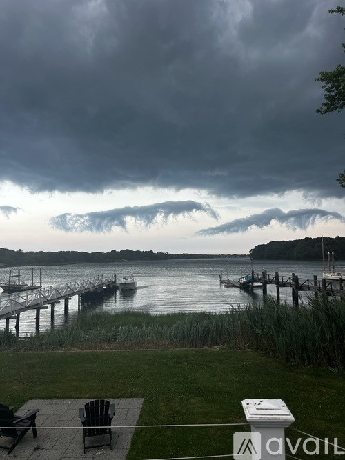 A stormy sky over a lake with a dock and a bench in the foreground.