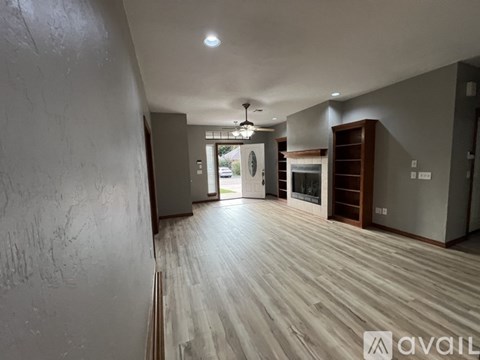 A spacious room with wooden flooring and a large window.