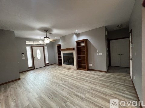 A spacious living room with a fireplace and a ceiling fan.