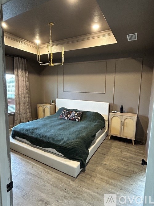 A bedroom with a bed, nightstand, and a chandelier.