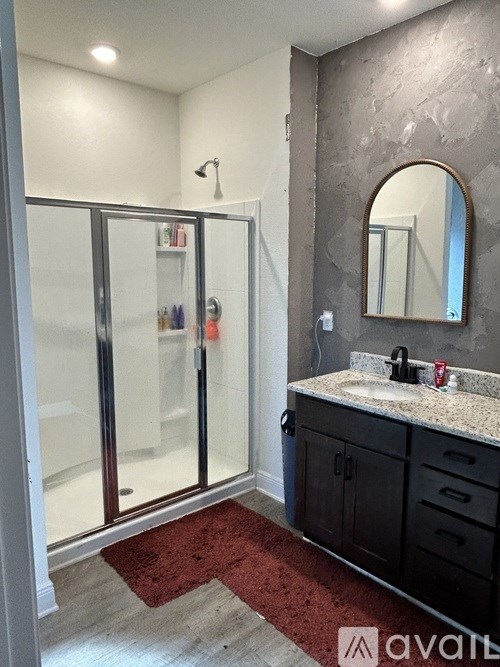 A bathroom with a sink, mirror, and shower.