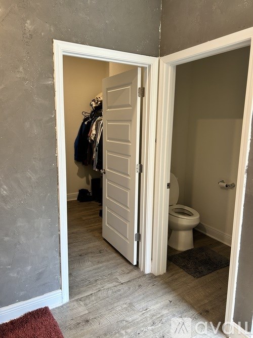 A bathroom with a toilet and a doorway leading to a hallway.