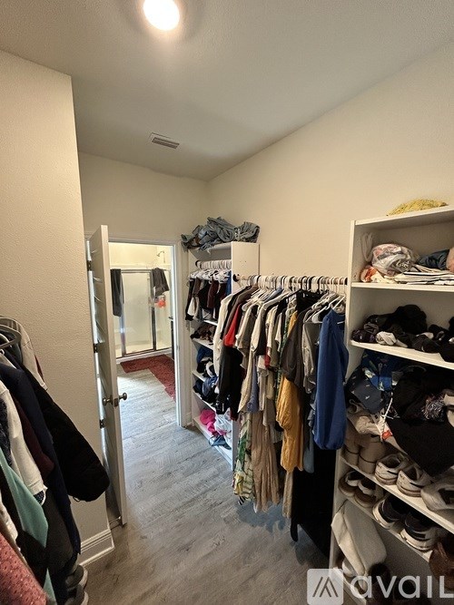 A walk in closet with clothes and shoes.