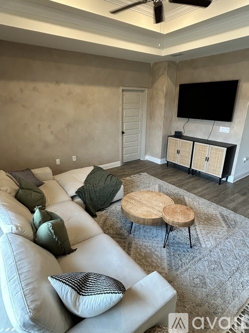 A living room with a white couch and a round wooden table.