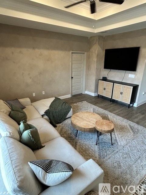 A living room with a white couch and a round wooden table.